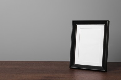 Empty square frame on wooden table, space for text