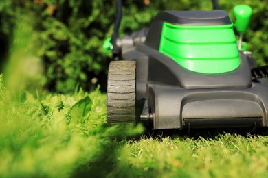 Cutting green grass with lawn mower in garden, closeup