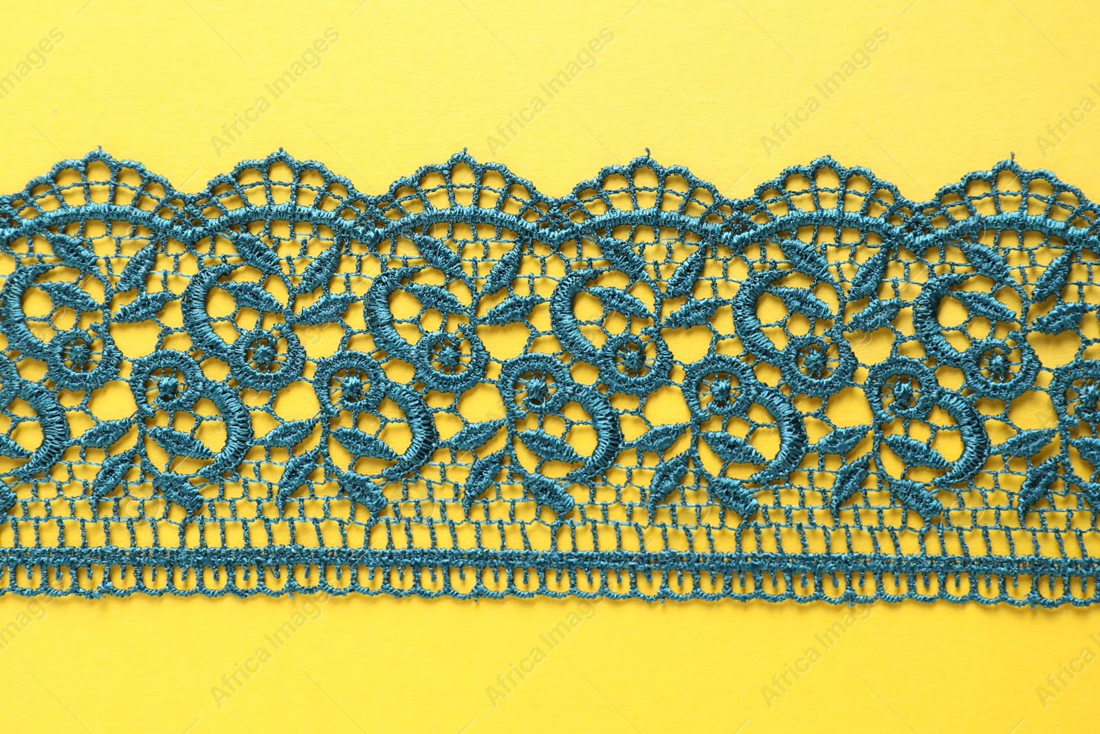 Photo of Green lace on yellow background, top view