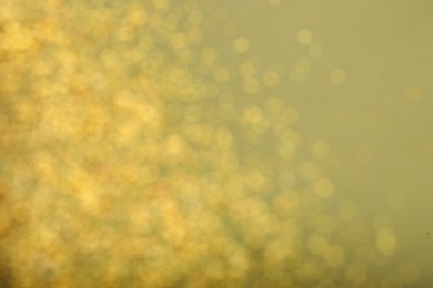 Photo of Blurred view of golden lights on pale green background. Bokeh effect