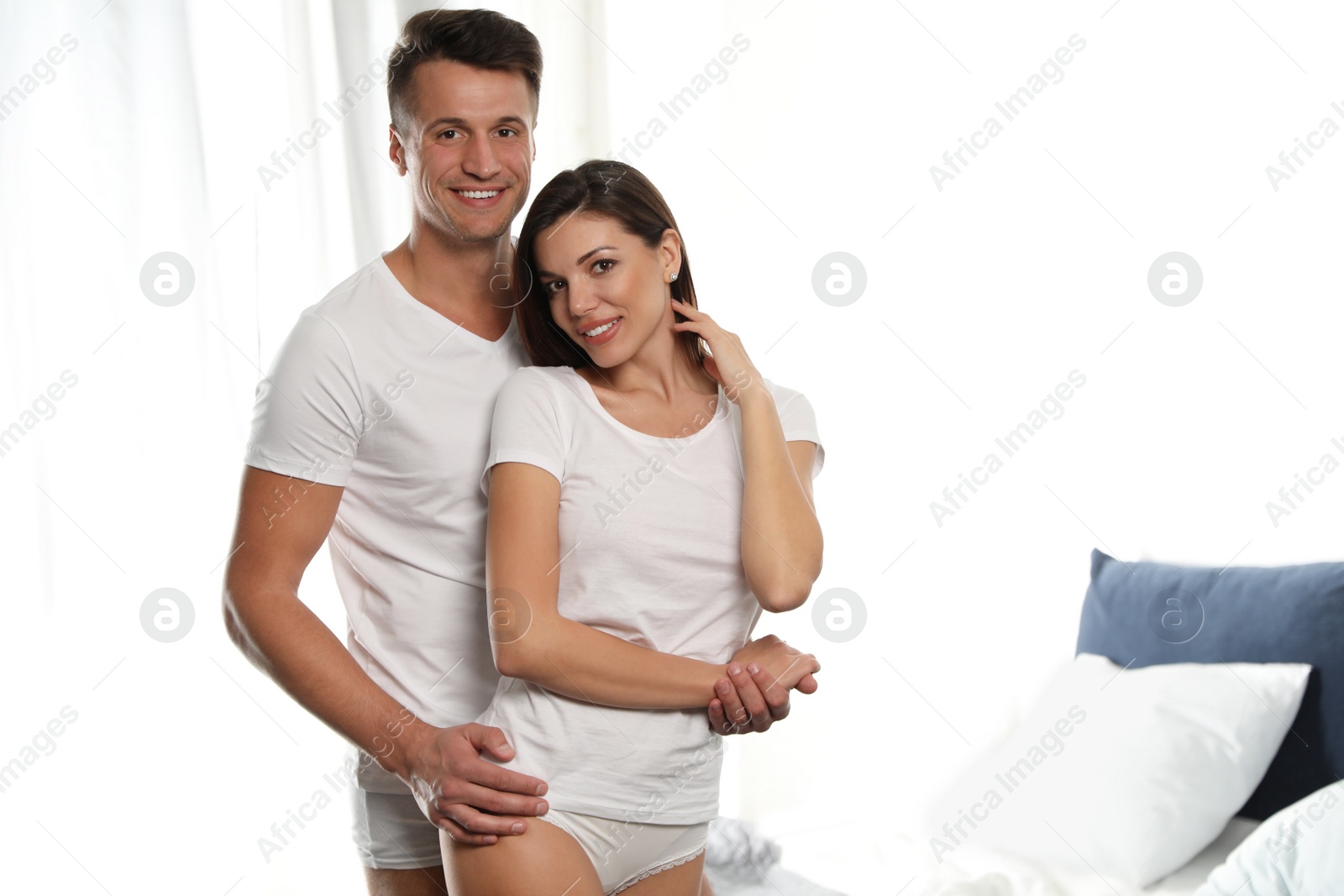 Photo of Happy couple wearing underwear in modern bedroom