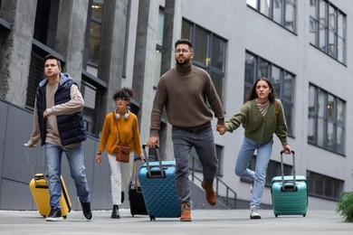 Photo of Being late. Group of people with suitcases running outdoors