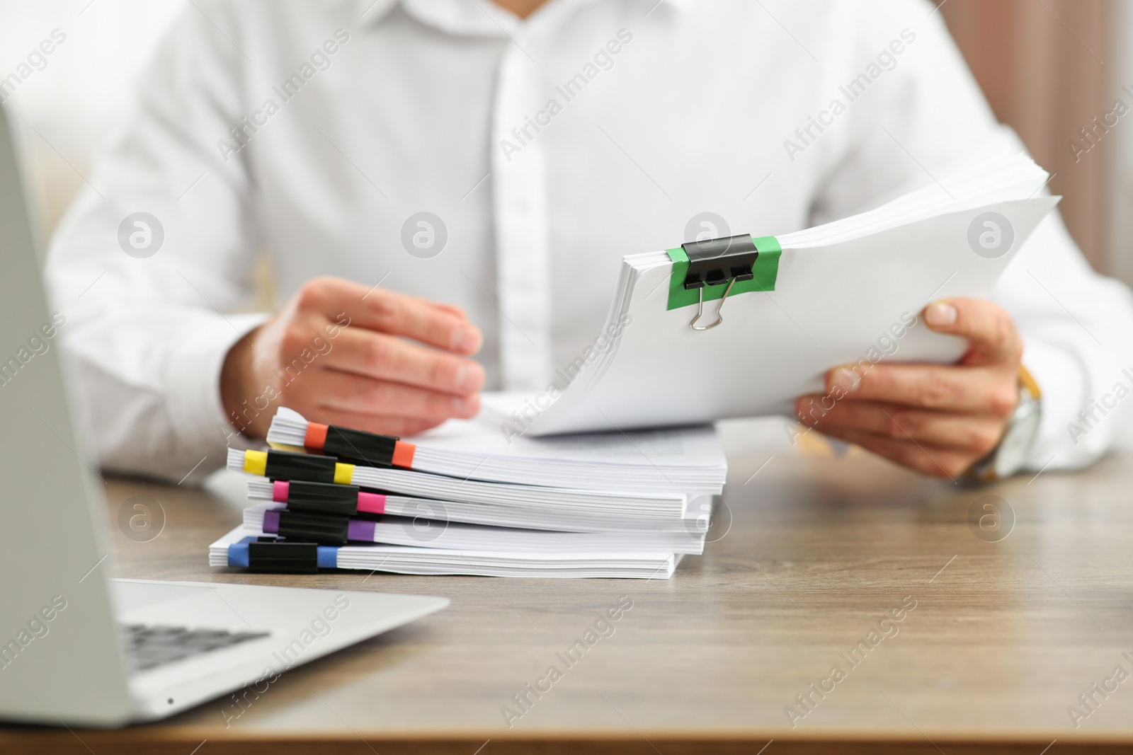 Photo of Man working with documents at wooden table in office, closeup