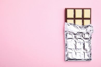 Photo of Tasty chocolate bar on pink background, top view. Space for text