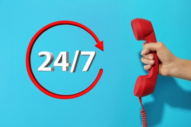 Image of 24/7 hotline service. Woman holding handset on light blue background, closeup