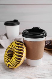 Tasty donut and cup of hot drink on white wooden table