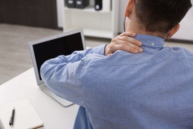 Photo of Man suffering from neck pain in office, back view