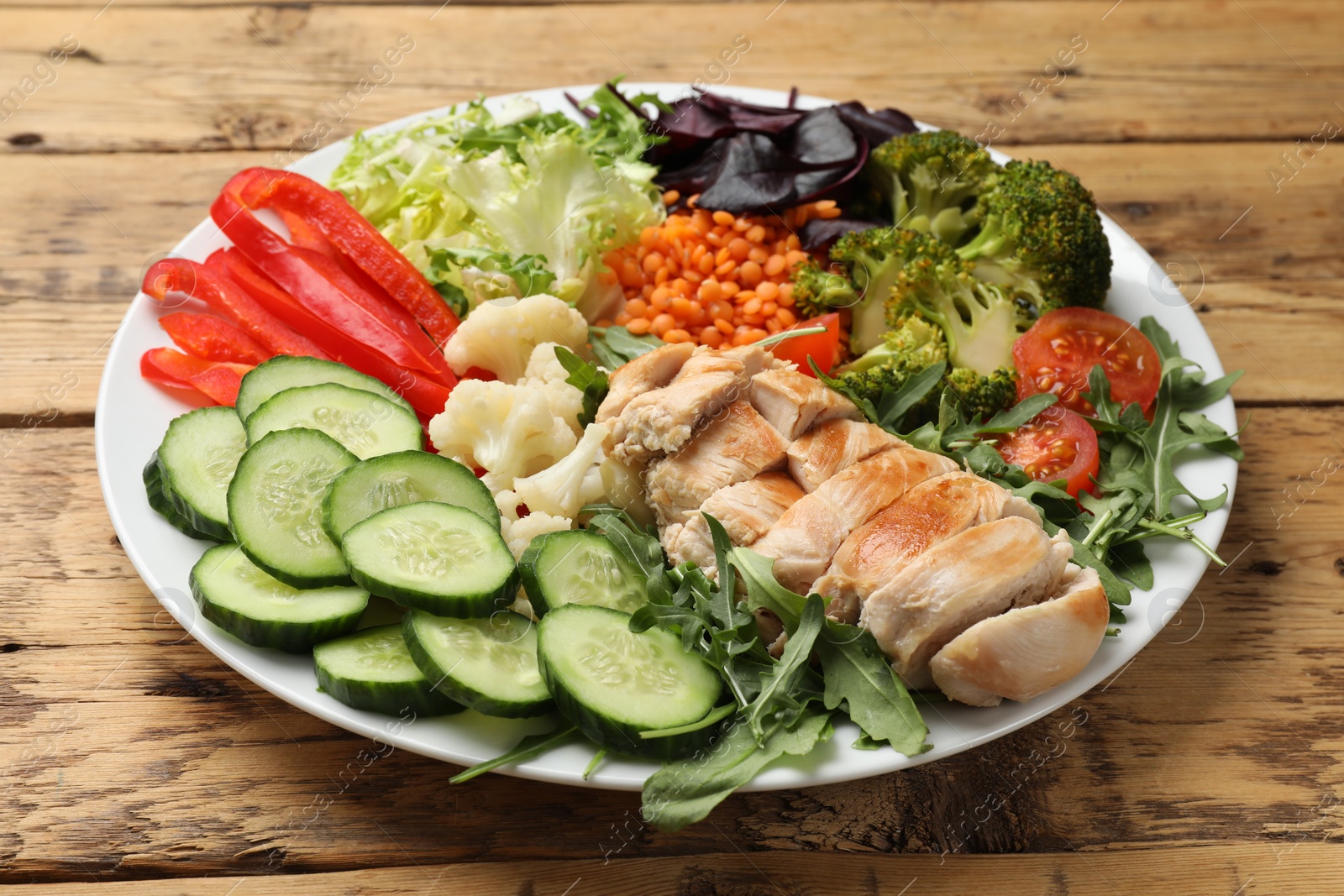 Photo of Balanced diet and healthy foods. Plate with different delicious products on wooden table, closeup