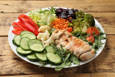 Photo of Balanced diet and healthy foods. Plate with different delicious products on wooden table, closeup