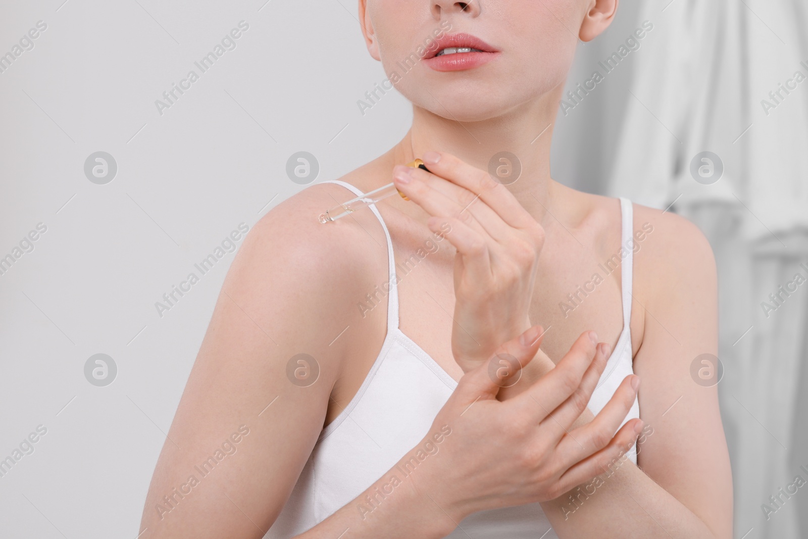 Photo of Woman applying essential oil onto shoulder in bathroom, closeup