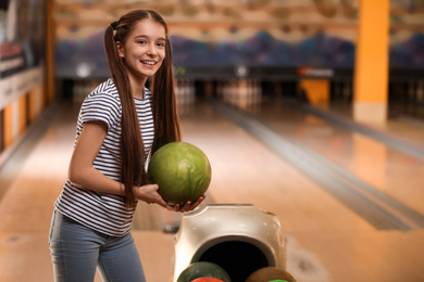 Photo of Preteen girl with ball in bowling club. Space for text