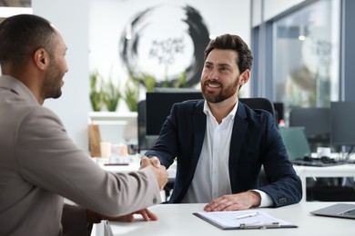 Lawyer shaking hands with client at table in office