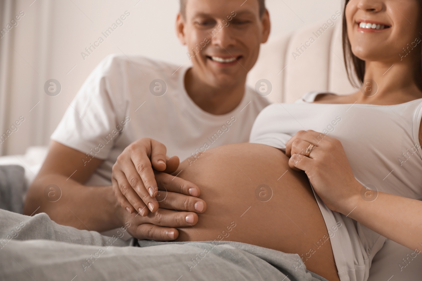 Photo of Young pregnant woman with her husband indoors, closeup