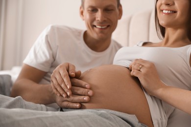 Young pregnant woman with her husband indoors, closeup