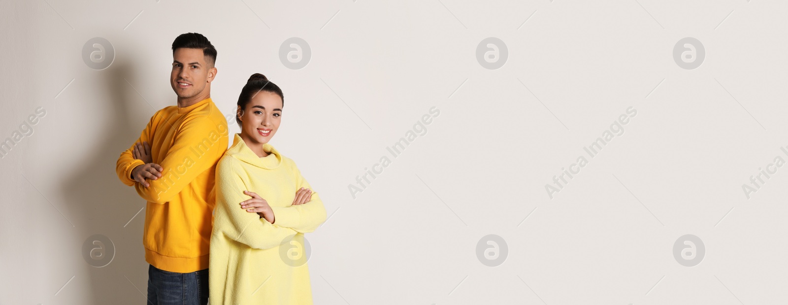 Photo of Happy couple wearing yellow warm sweaters on white background