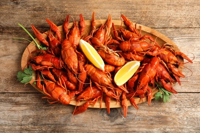 Photo of Delicious boiled crayfishes on wooden table, top view