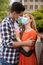 Couple in medical masks trying to kiss outdoors