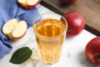 Photo of Glass of delicious cider and ripe red apples on white marble table