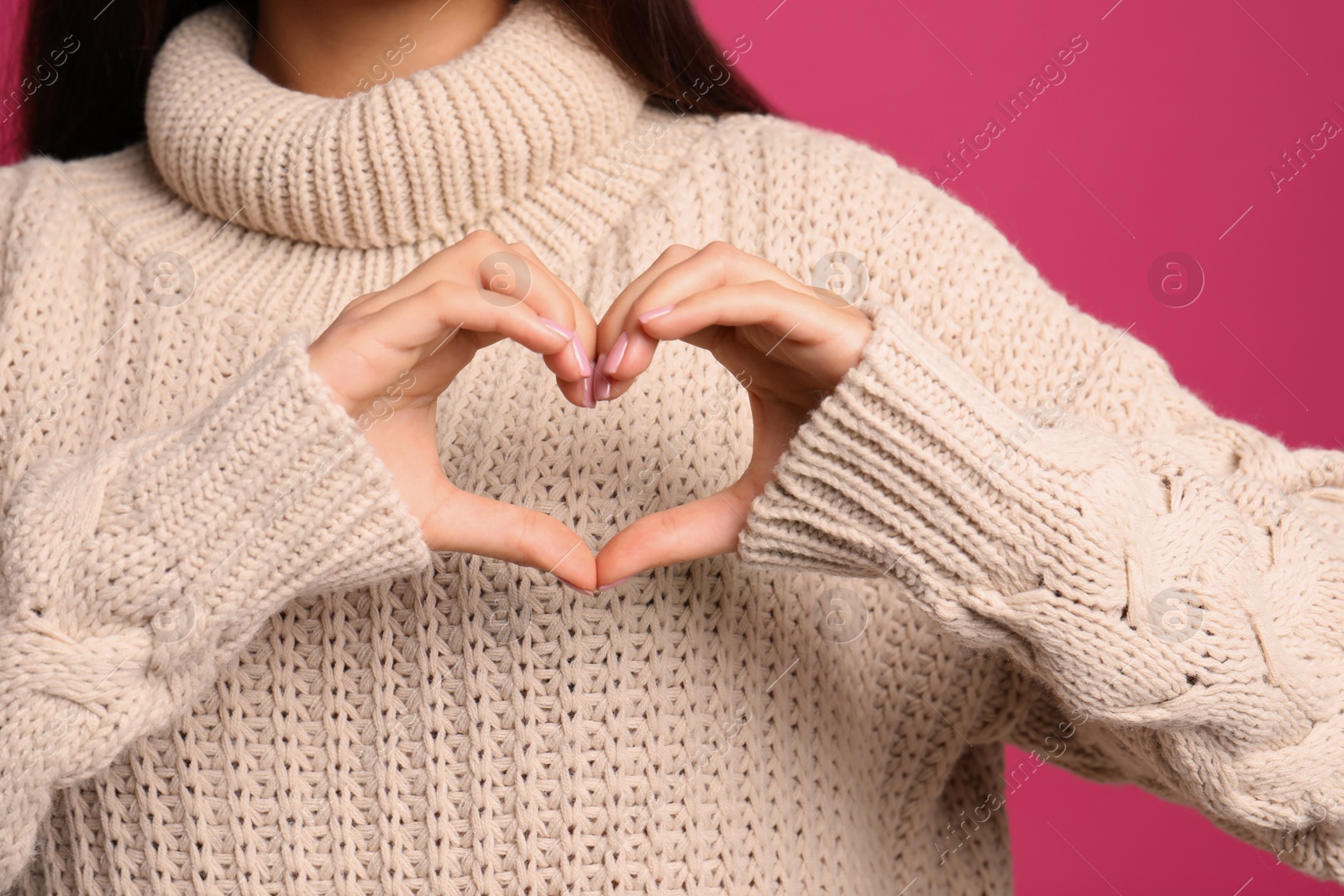 Photo of Woman making heart with her hands on color background, closeup