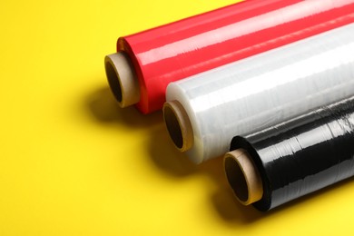 Photo of Different plastic stretch wrap films on yellow background. Space for text