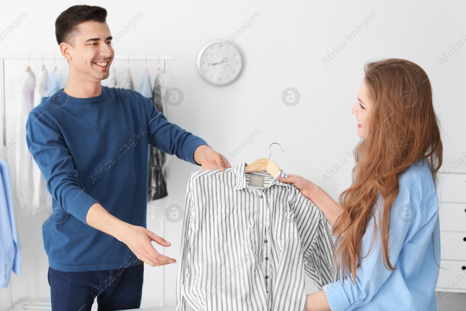 Photo of Young woman giving shirt to dry-cleaner's worker