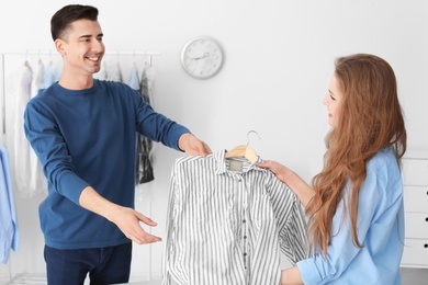 Young woman giving shirt to dry-cleaner's worker