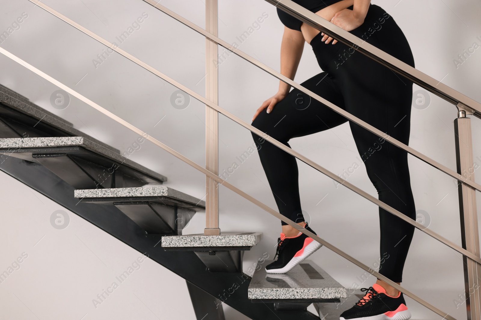 Photo of Overweight woman suffering from pain in left side while running upstairs indoors, closeup. Space for text