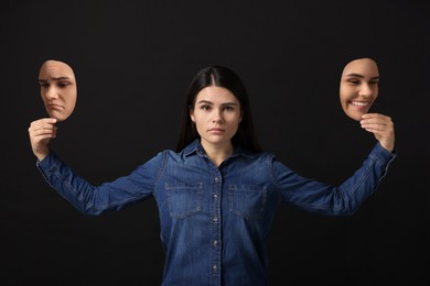 Woman holding masks with her face showing different emotions on black background. Balanced personality