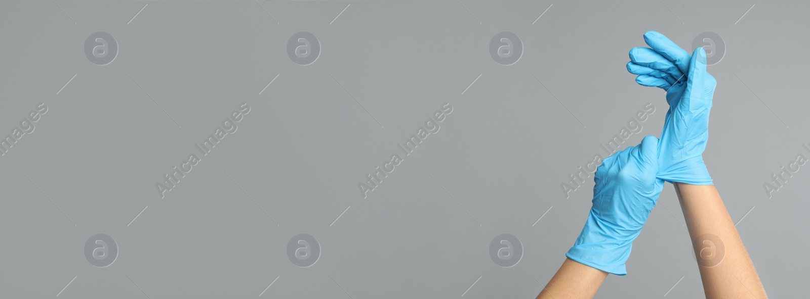 Image of Doctor wearing medical gloves on light grey background, closeup. Banner design with space for text 