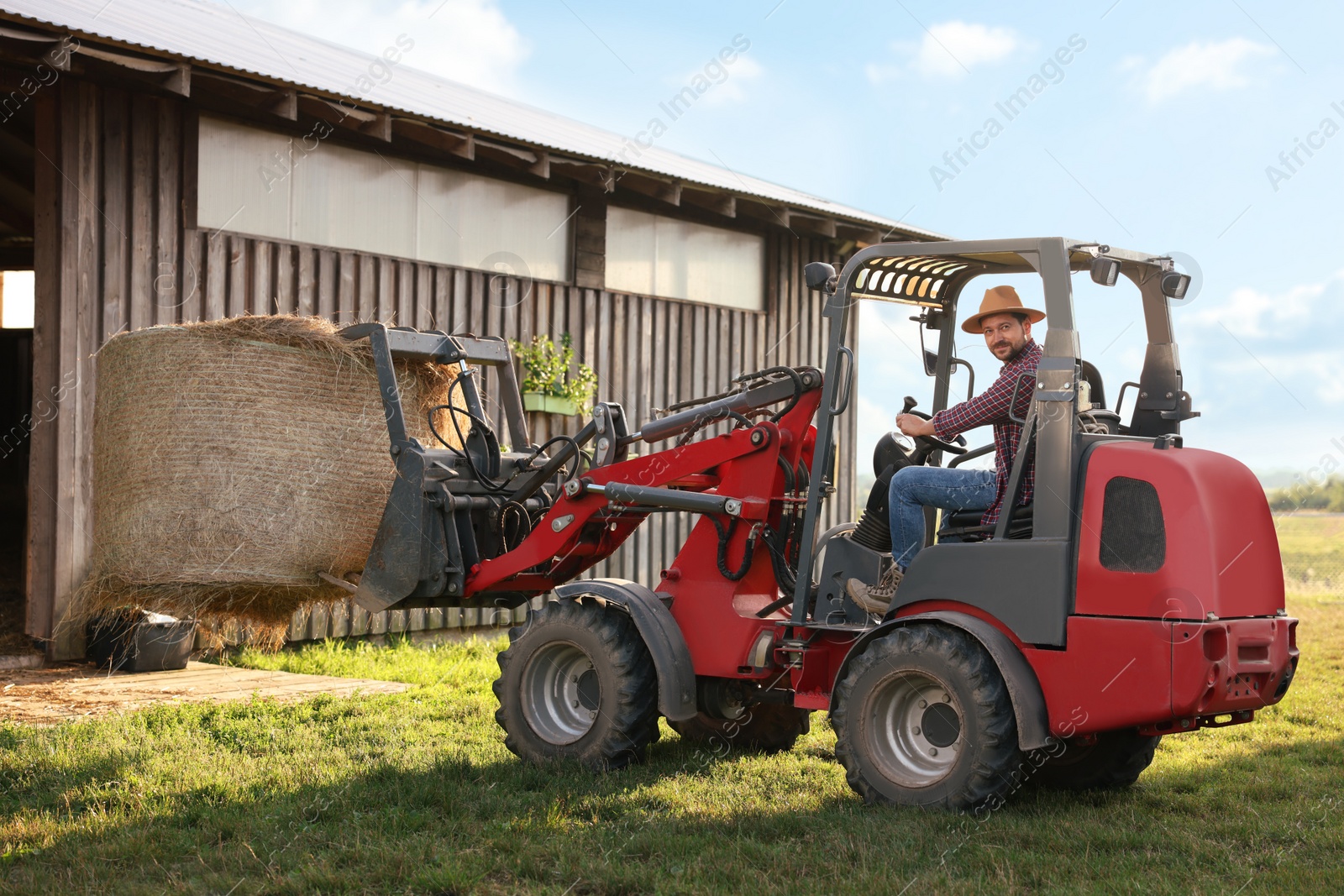 Photo of Farmer in loader transporting hay on farm. Agriculture equipment