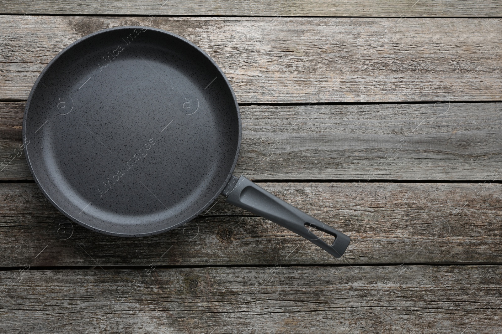 Photo of New non-stick frying pan on wooden table, top view. Space for text