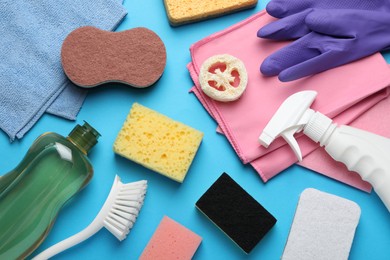 Photo of Many different sponges and other cleaning products on light blue background, flat lay