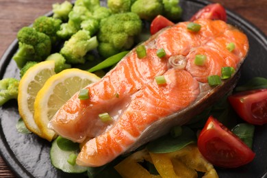 Photo of Healthy meal. Grilled salmon steak, green onion, lemon and vegetables on table, closeup
