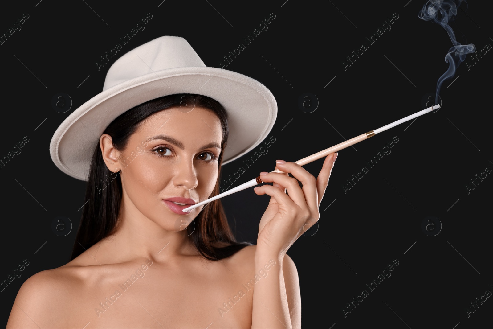 Photo of Woman using long cigarette holder for smoking on black background