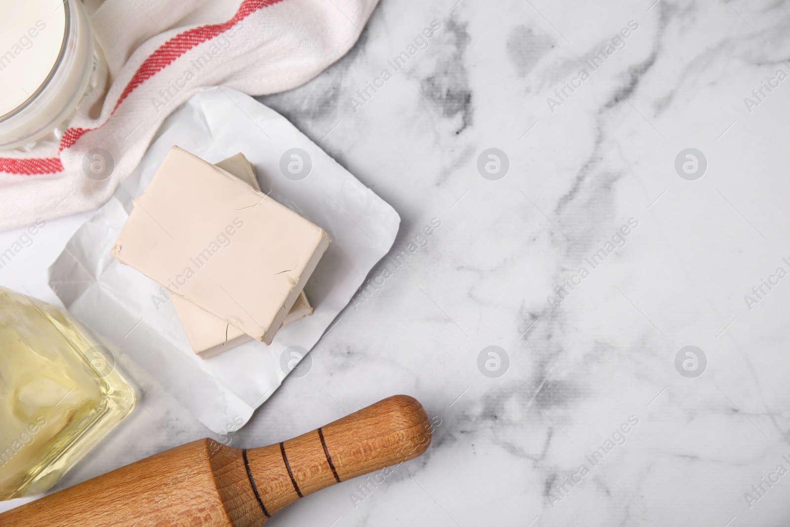 Photo of Yeast and food ingredients on white marble table, flat lay. Space for text