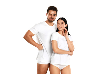 Young couple in white t-shirts and underwear on light background
