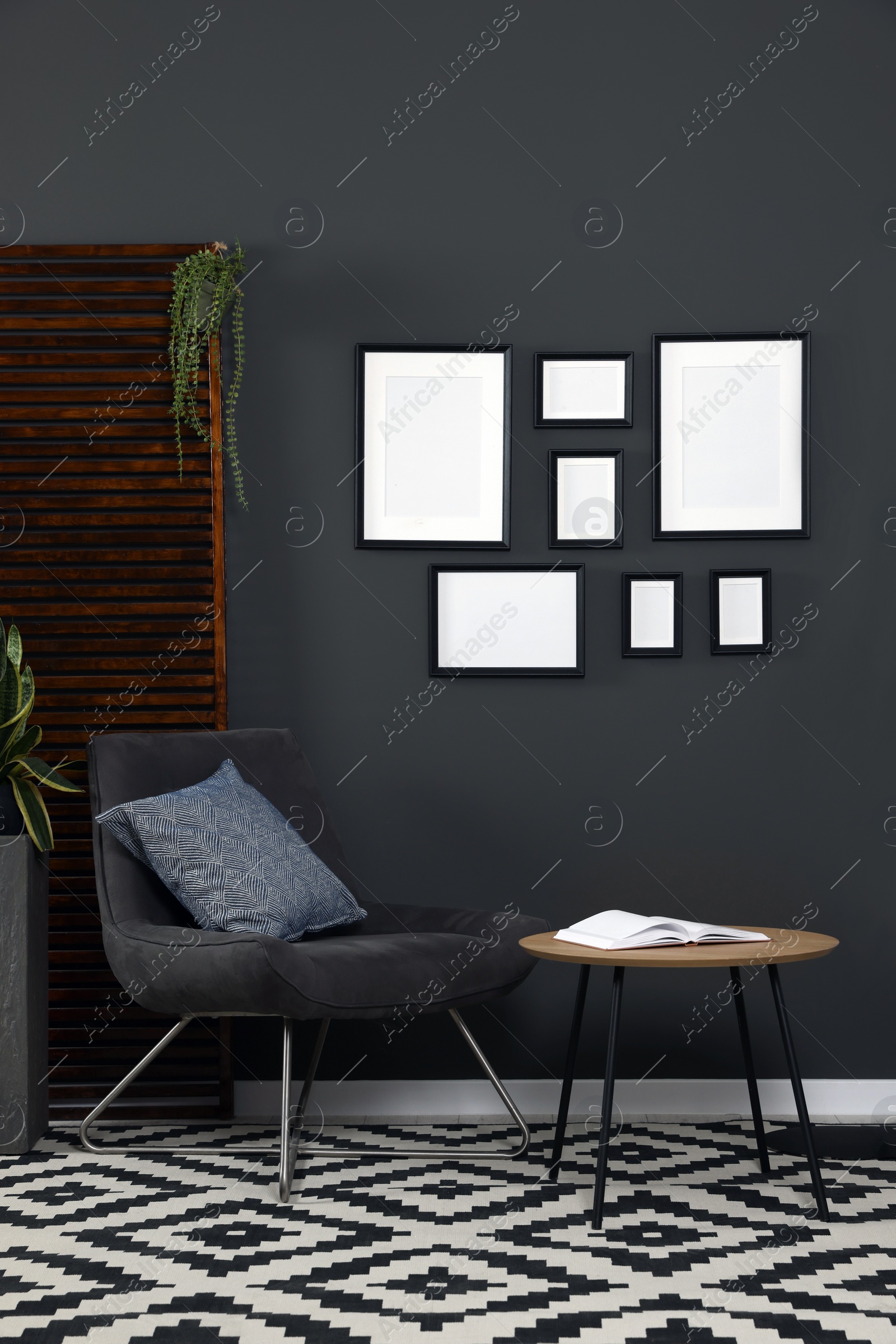 Photo of Empty frames hanging on black wall in stylish room. Mockup for design