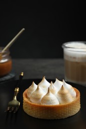 Photo of Tartlet with meringue served on black table, closeup and space for text. Delicious dessert