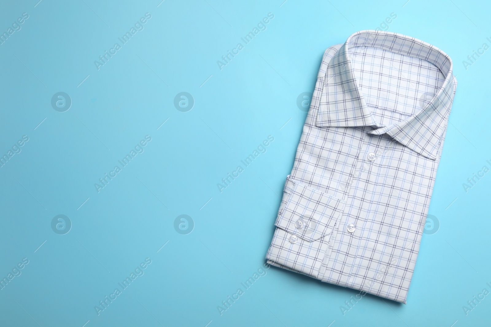 Photo of Male stylish shirt with pattern on light blue background, top view. Space for text