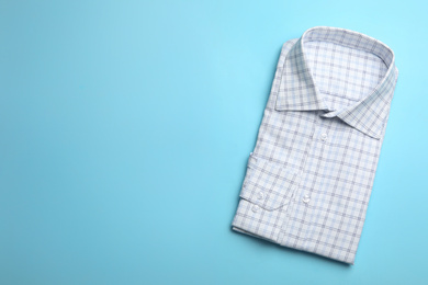 Photo of Male stylish shirt with pattern on light blue background, top view. Space for text