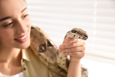 Photo of Young woman with her boa constrictor at home, closeup. Exotic pet