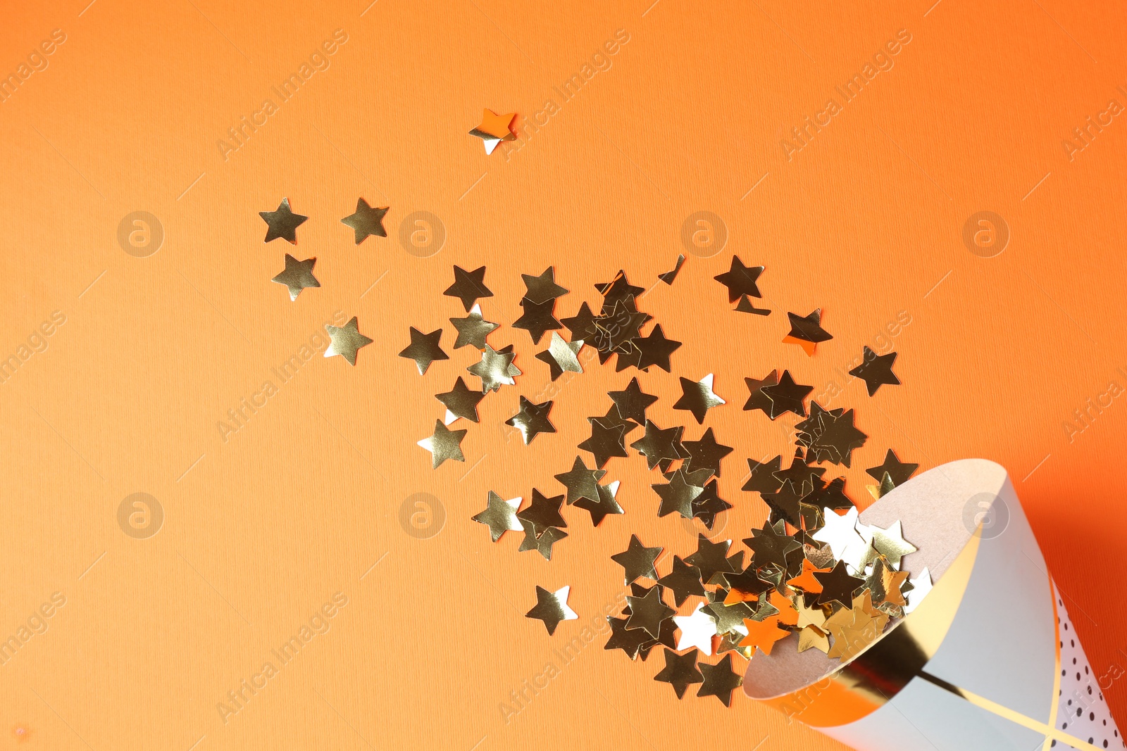 Photo of Party hat and confetti on orange background, top view