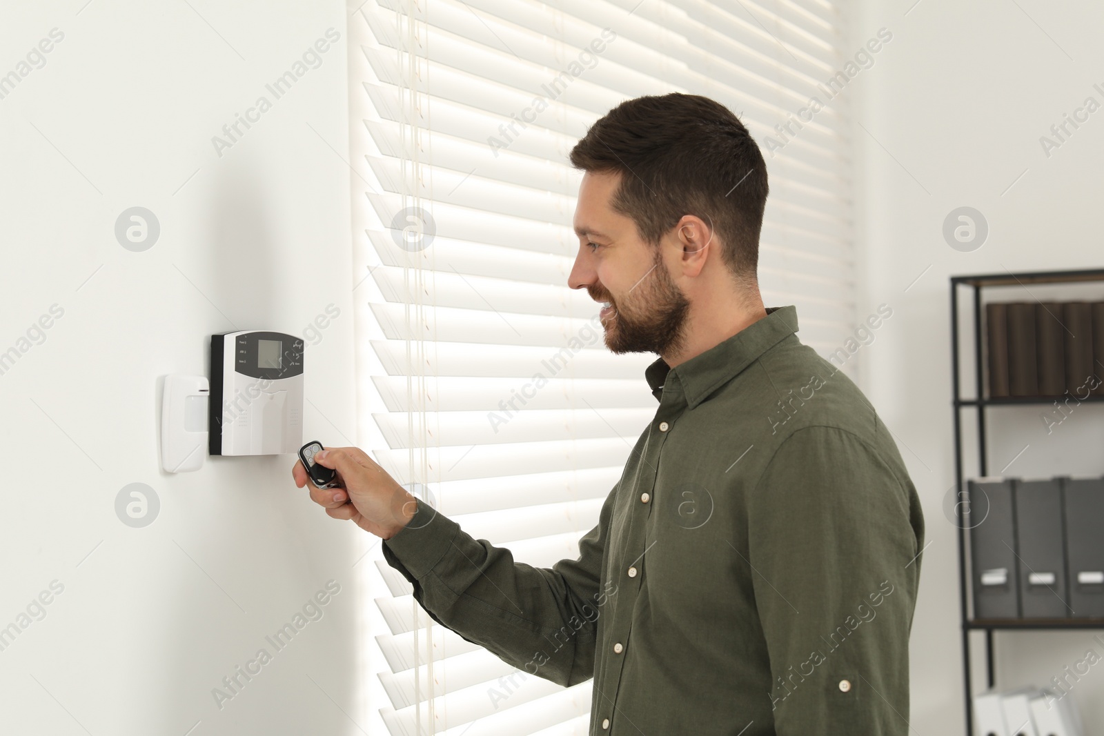 Photo of Home security system. Man using alarm key fob indoors