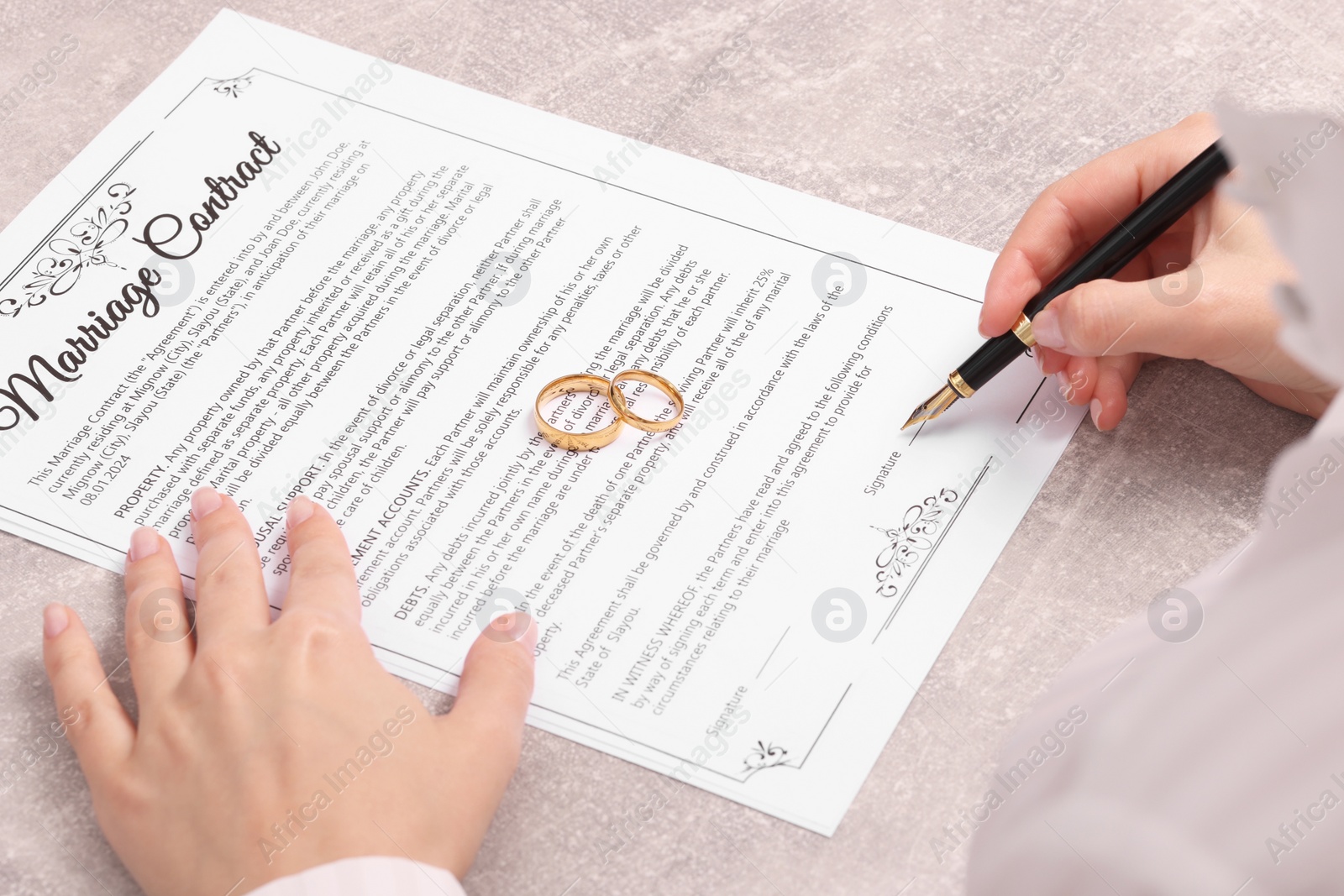 Photo of Woman signing marriage contract at light grey table, closeup