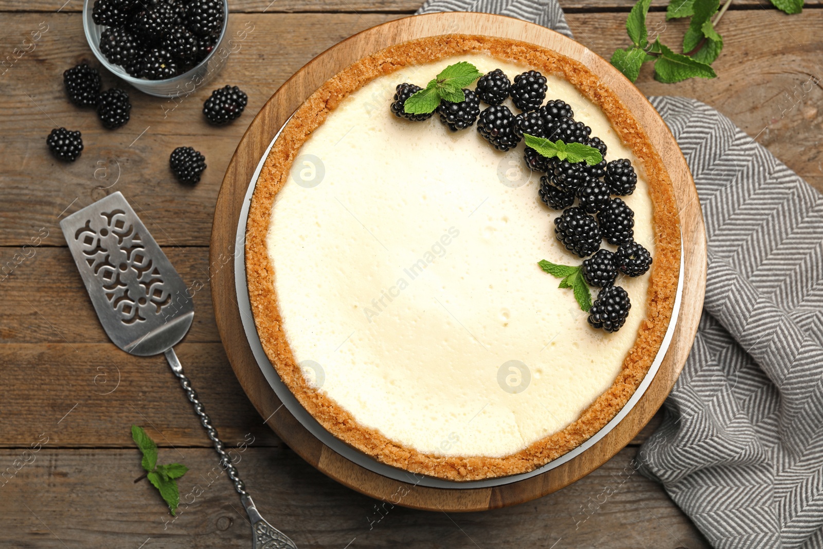 Photo of Delicious cheesecake decorated with blackberries on wooden table, flat lay