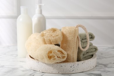 Photo of Loofah sponges, towels and cosmetic products on white marble table
