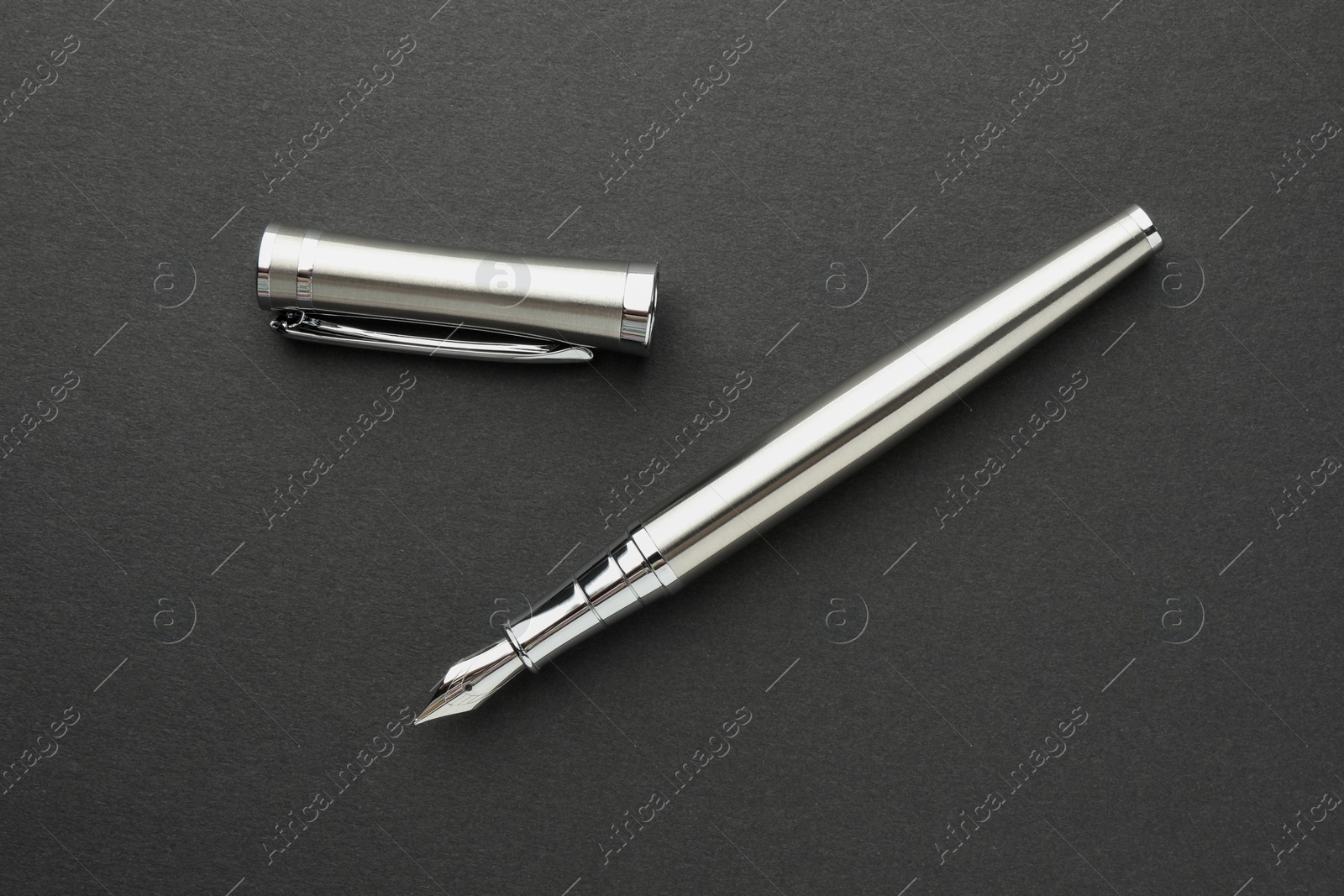 Photo of Stylish silver fountain pen with cap on dark background, flat lay