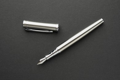 Stylish silver fountain pen with cap on dark background, flat lay