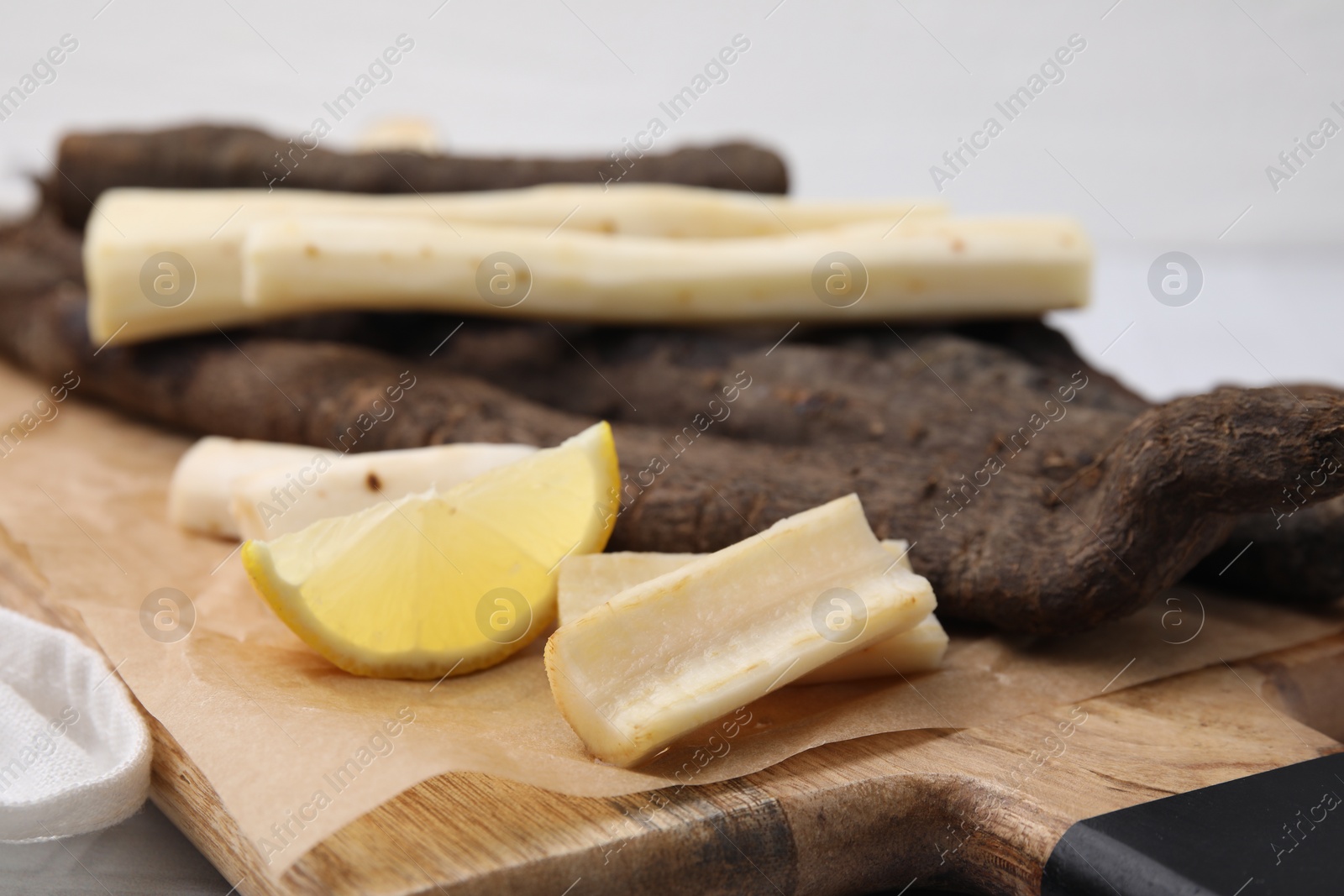 Photo of Raw salsify roots and lemon on table, closeup