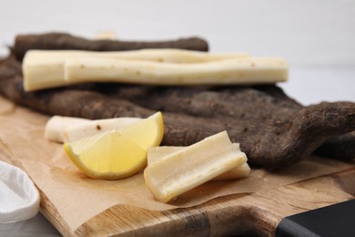 Photo of Raw salsify roots and lemon on table, closeup